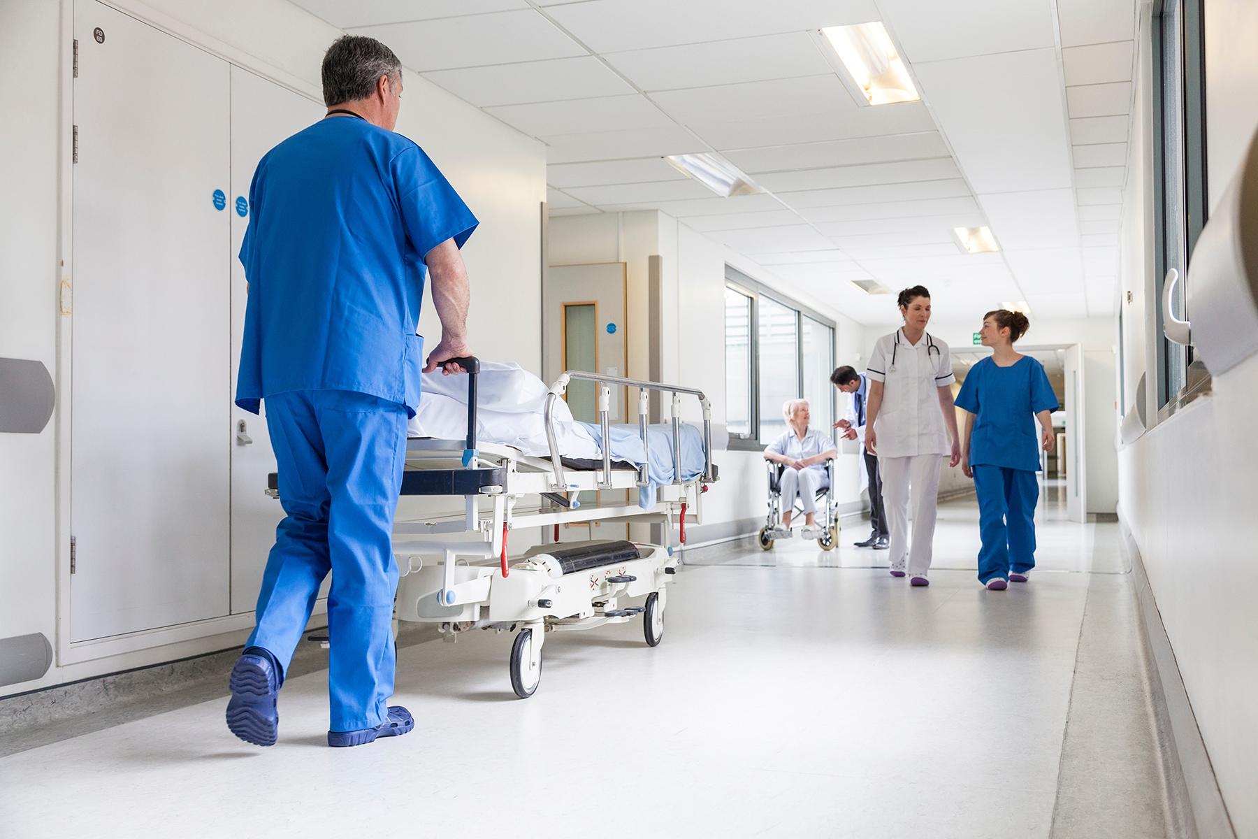 Ein Pfleger schiebt ein Krankenbett über einen Flur