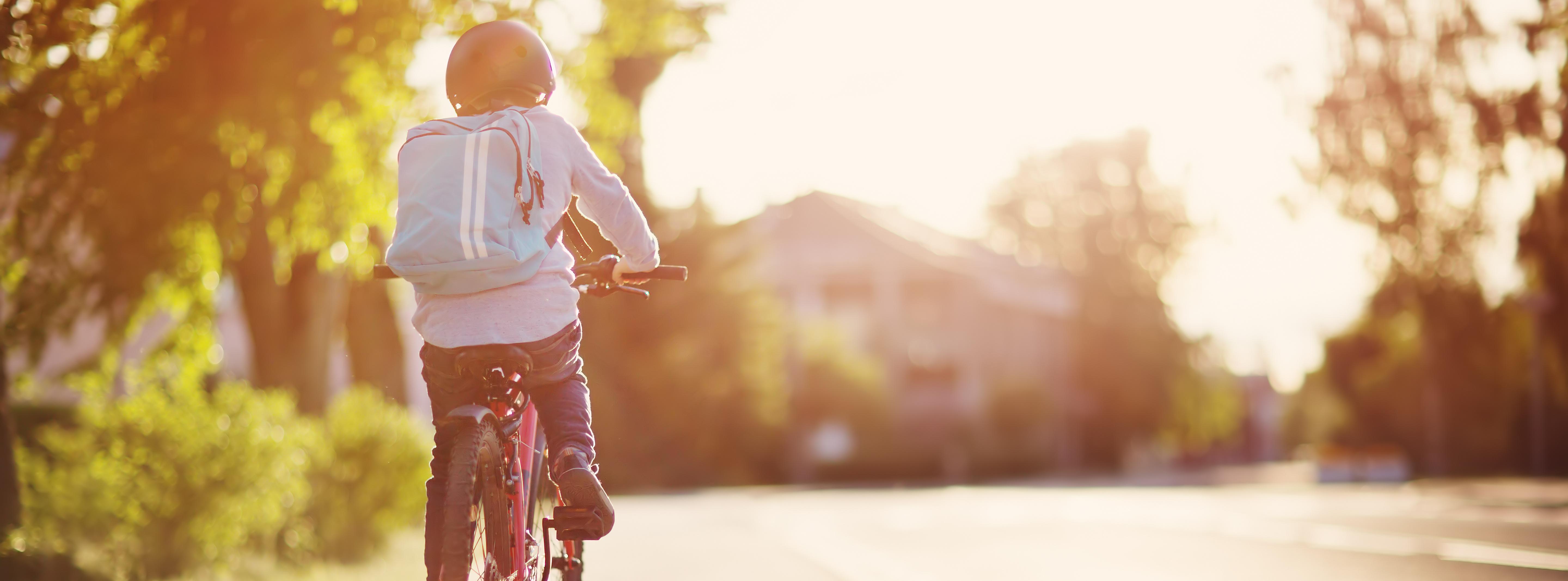 Kind fährt mit dem Fahrrad auf dem Seitenstreifen einer Straße