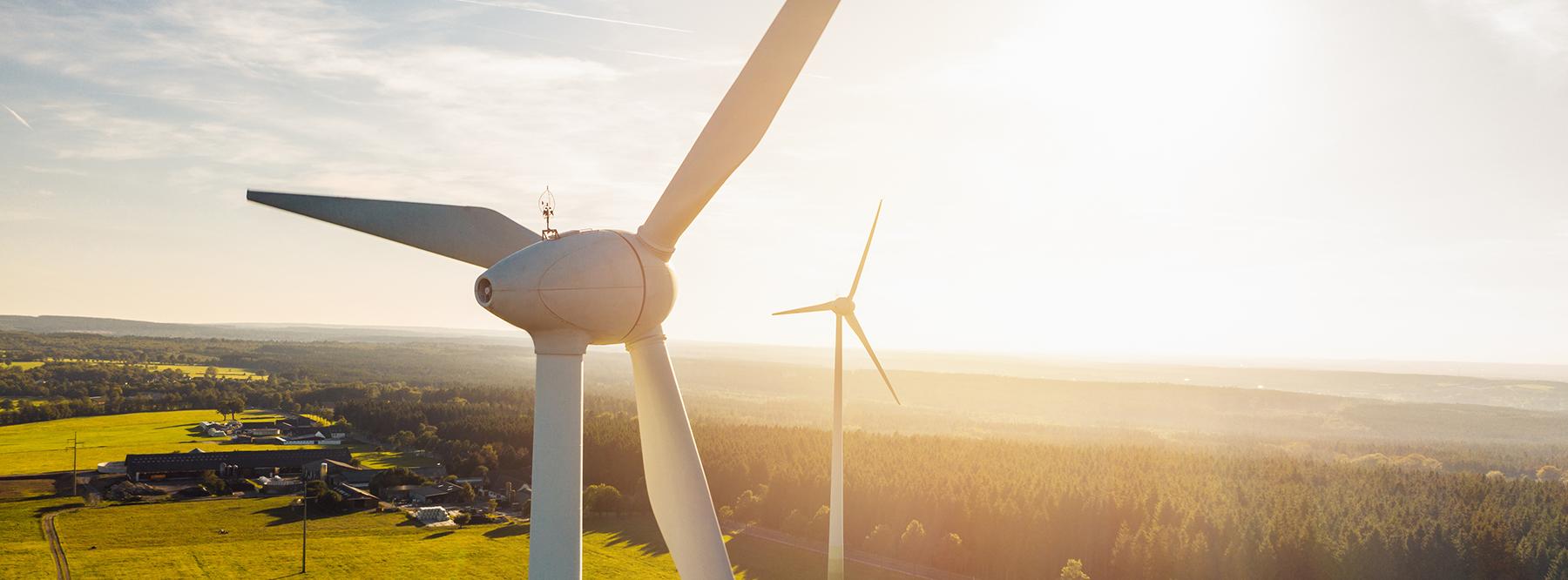 Auf dem Bild sind im Vordergrund eine Windkraftanlage und im Hintergrund eine weitere zu sehen.