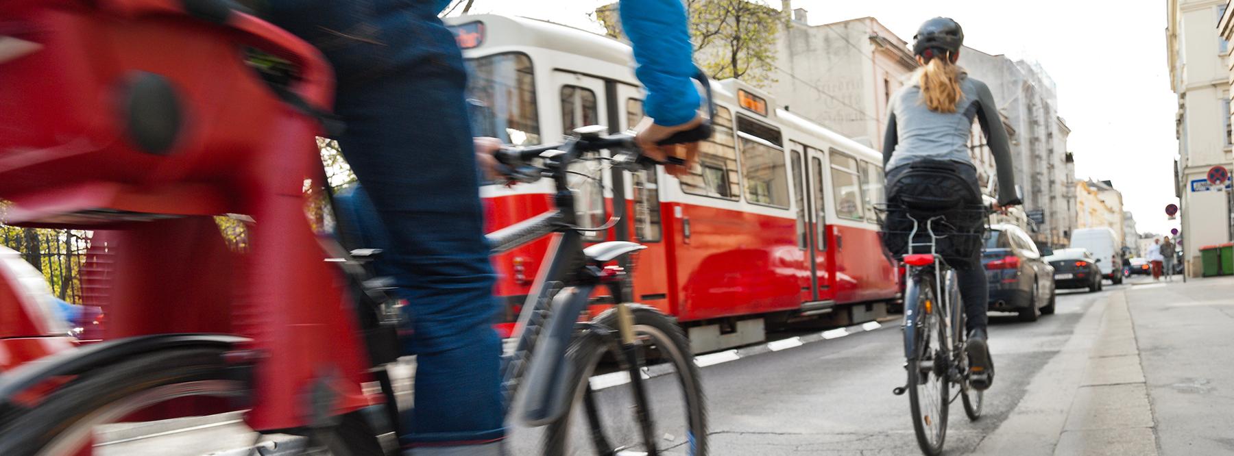 Gefährliche Begegnung zwischen Radfahrern, Autos und einer Straßenbahn am Ende eines markierten Radwegs auf einer stark befahrenen Straße.