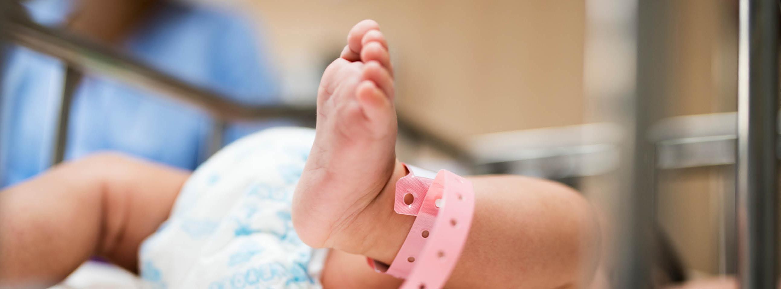 Ein Neugeborenes mit Namensschild im Krankenhaus