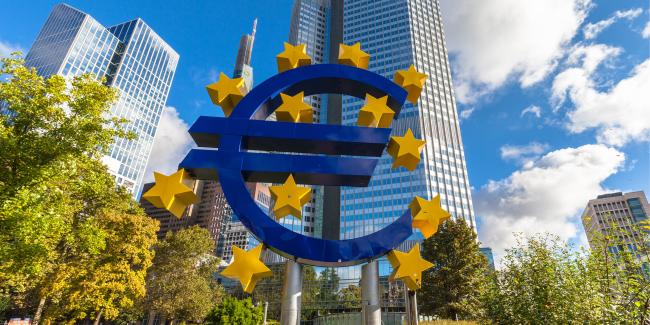 Euro-Zeichen, im Hintergrund Hochhäuser