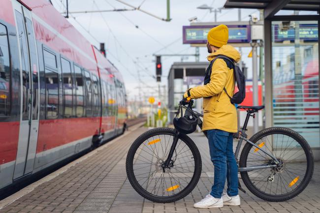 Das Bild zeigt einen Mann am Bahnsteig mit einem Fahrrad.