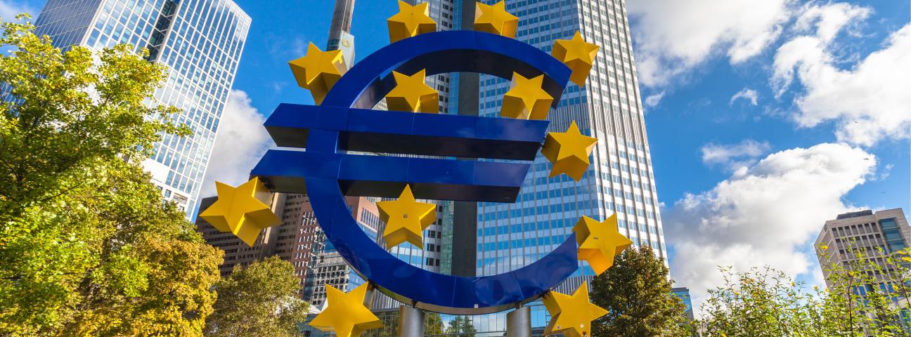 Euro-Zeichen, im Hintergrund Hochhäuser