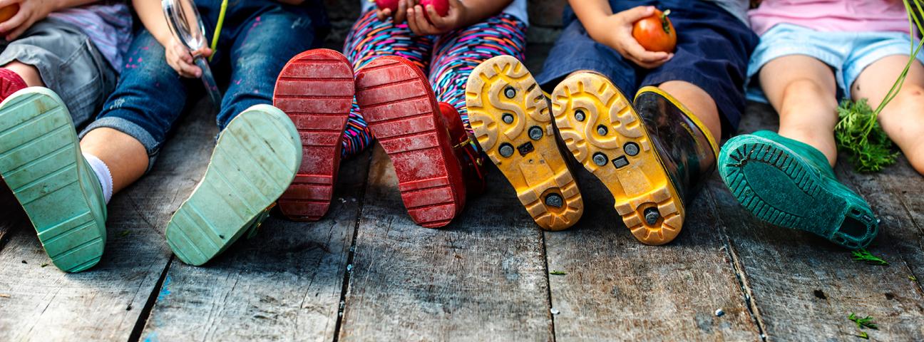 Kinder, die nebeneinander sitzen und Gemüse in der halten.