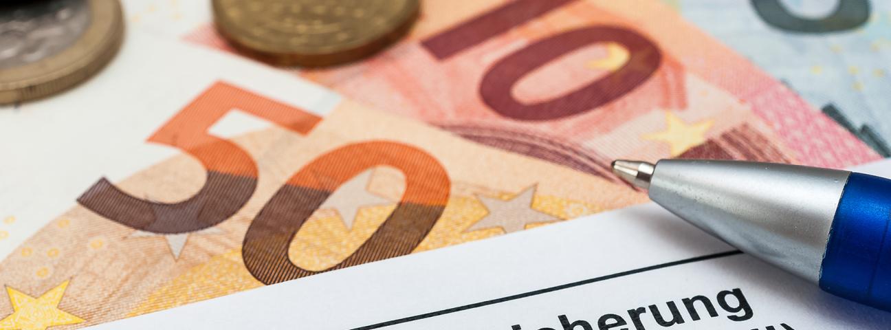 Euro-Scheine, Münzen, Antrag auf Grundsicherung und Kugelschreiber