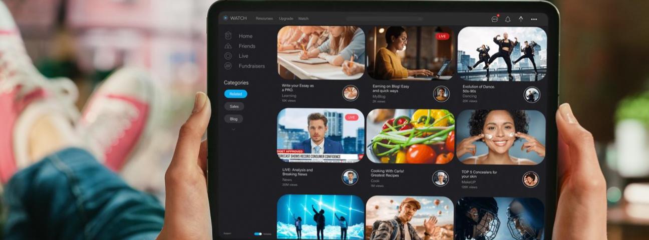 Eine Person hält ein Tablet, auf dem Vorschaubilder verschiedener Videos zu sehen sind