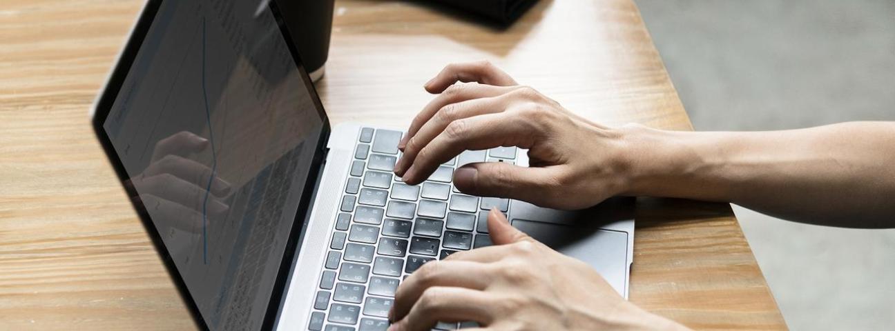 Person tippt auf einem Laptop