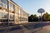 Schulgebäude und Schulhof mit Basketballkörben in der Abendsonne