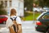 Mädchen mit Rucksack überquert einen Zebrastreifen auf dem Weg zur Schule