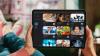 Eine Person hält ein Tablet, auf dem Vorschaubilder verschiedener Videos zu sehen sind
