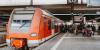 Ein Regionalzug der Linie S11 mit dem Ziel Bergisch Gladbach hält an einem Gleis eines Bahnhofs. Menschen steigen ein und aus.