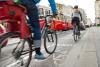 Gefährliche Begegnung zwischen Radfahrern, Autos und einer Straßenbahn am Ende eines markierten Radwegs auf einer stark befahrenen Straße.
